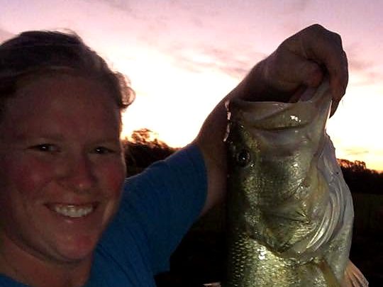 Hollie holding up a largemouth bass at sunset