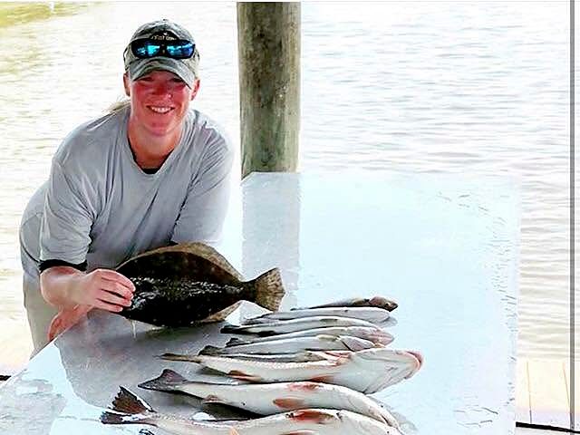 Hollie at the dock with a flounder and a table full of redfish and speckled trout