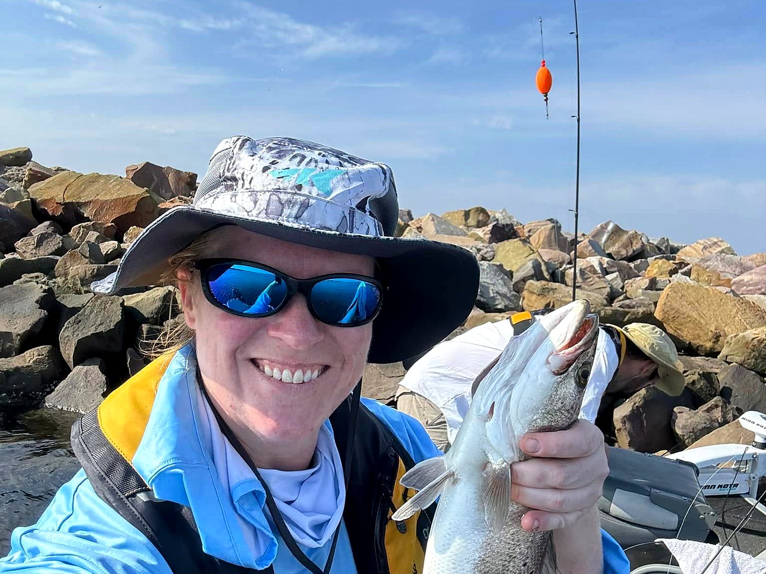 Hollie holding a speckled trout by the rocks