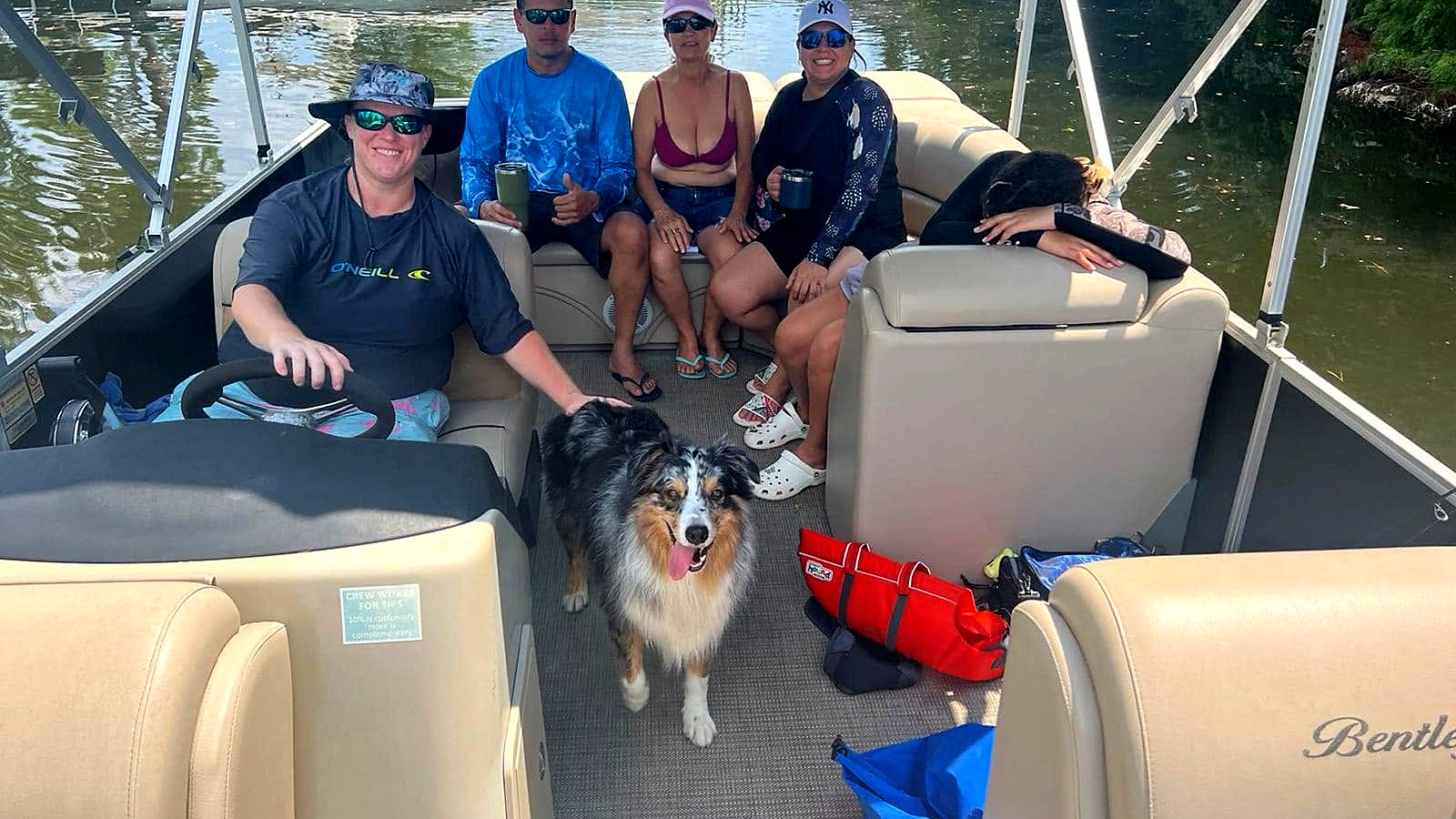 Friends and a dog relaxing on a pontoon boat with Hollie at the helm